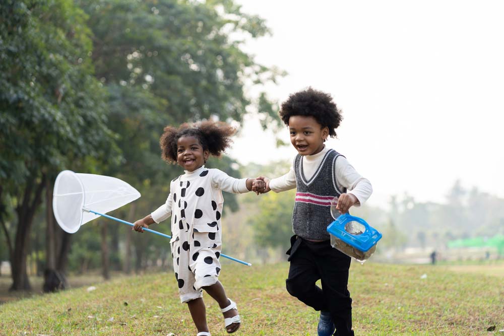 Children running and playing outdoors representing healthy smiles.