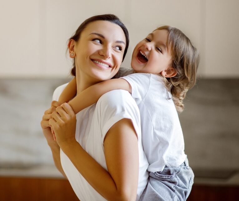 little girl hugging mom from behind