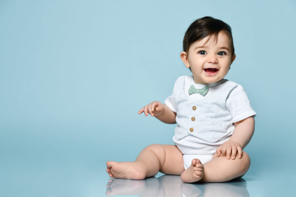 little boy in white body suit smiling
