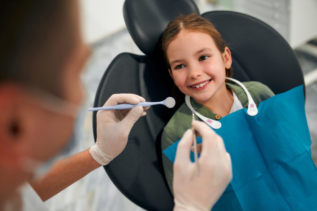 little girl sitting on dental chair smiling