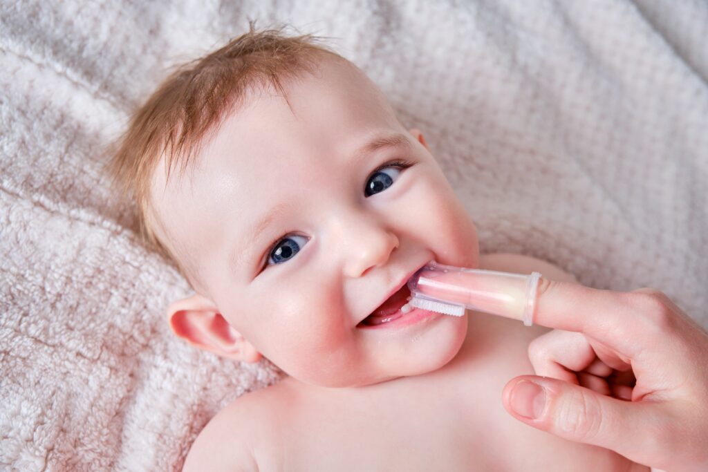 mother brushing baby's teeth with a finger brush